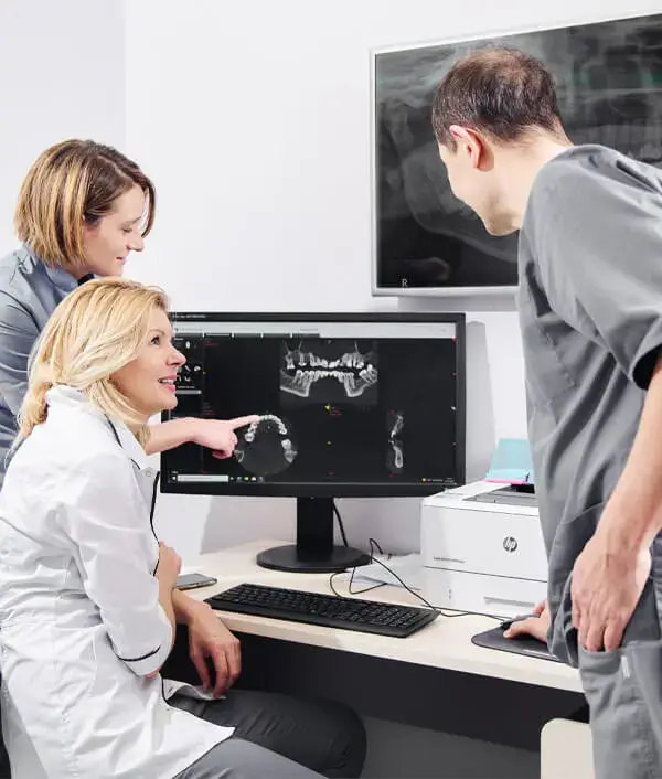 Trzy osoby oglądające zdjęcie rentgenowskie na komputerze na Stronie głównej.